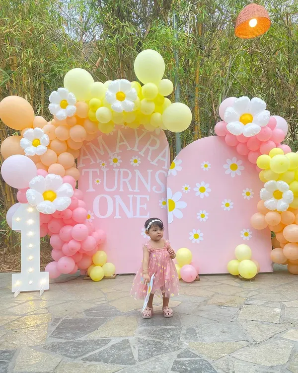 This is what a perfect first birthday looks like. For Amayra's big day, I created a cheerful daisy-themed backdrop with custom lettering, a light-up marquee number '1', and a beautiful organic balloon arch in shades of pink, orange, and yellow.