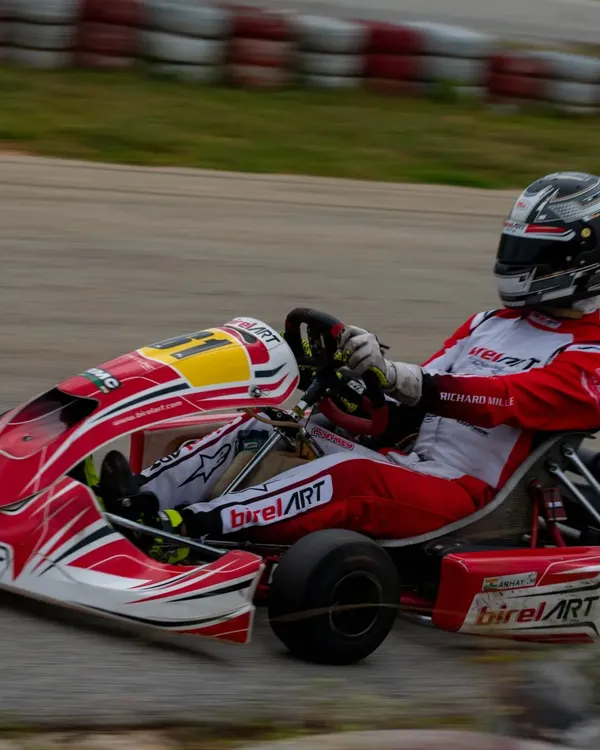 A Birel ART racing kart, expertly handled by one of our drivers, demonstrates pure speed and precision with motion blur highlighting its velocity on the track. This is the performance standard we set.