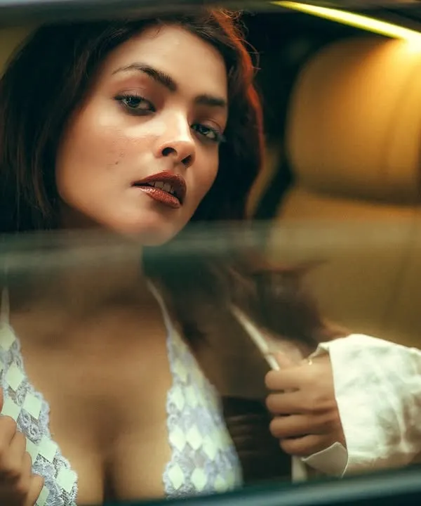 A moment of quiet allure, captured through the reflection of a car window. This intimate portrait plays with layers and light to create a sense of mystery and cinematic beauty.