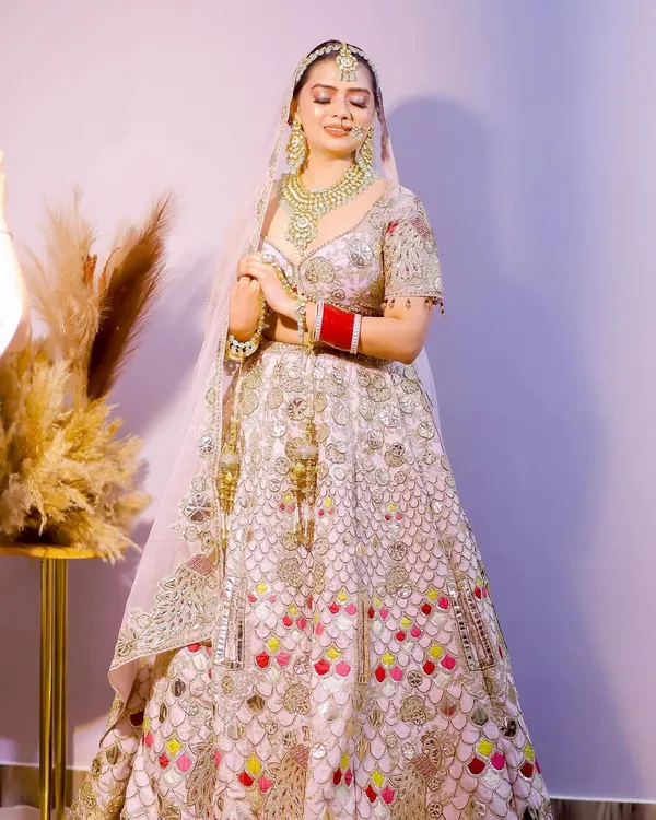 A stunning full-length portrait of the bride in her magnificent lehenga. The soft lighting and her serene expression capture her elegance and grace on the wedding day.