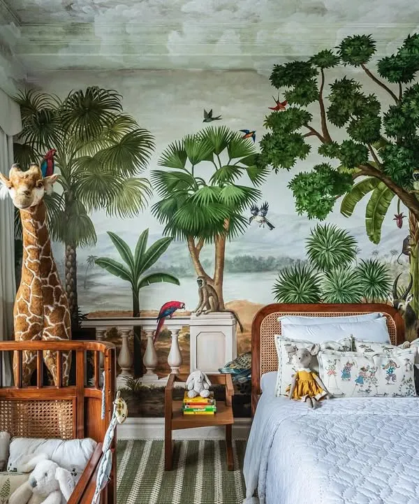 A complete view of this jungle-themed nursery, showing how the crib and toddler bed work together in the space. The hand-painted mural wraps around the room, creating a truly immersive and adventurous world for a little one.