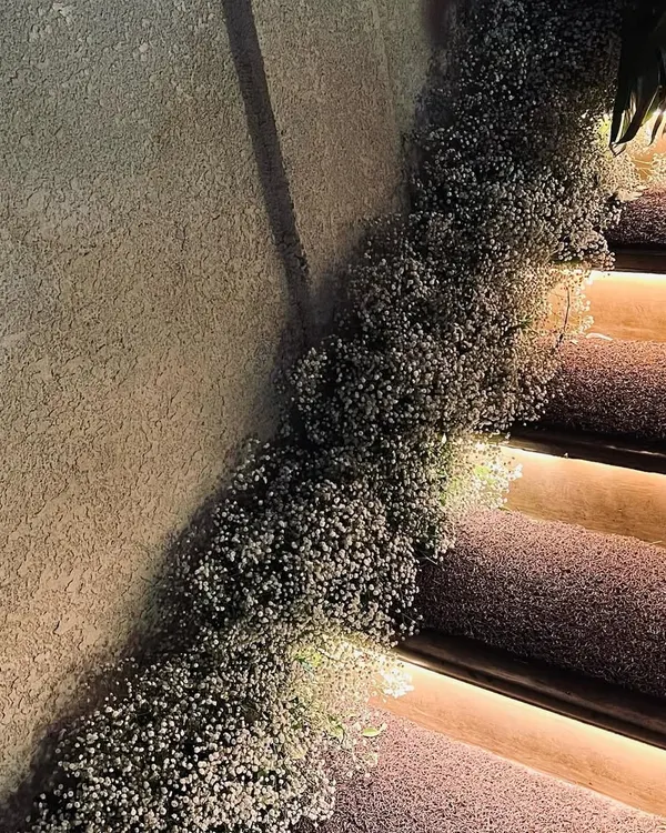 For a 25th-anniversary celebration, we created a romantic pathway by lining the staircase with a thick, cloud-like arrangement of baby's breath. The integrated soft lighting on the steps enhanced the dreamy and elegant effect, setting the mood right from the entrance.