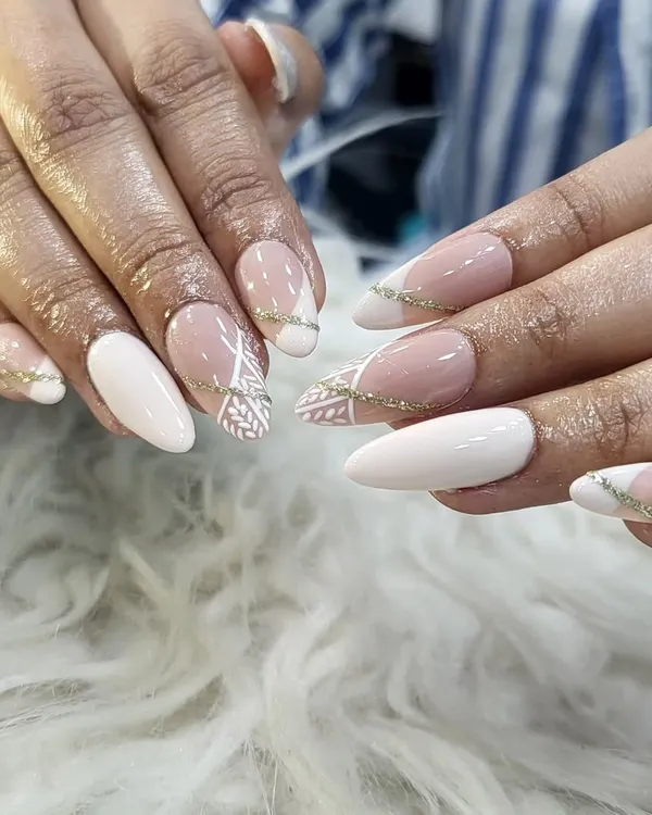 A beautiful and sophisticated set we designed for an engagement. This look features a mix of solid white and nude nails with delicate, hand-painted white patterns and a subtle gold glitter line for a touch of celebration.