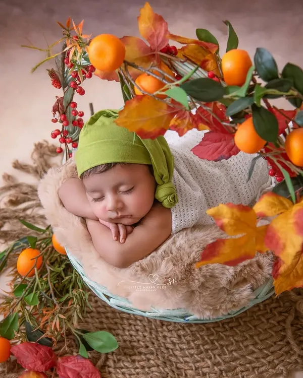 Wrapped in warmth and kissed by autumn colors. This cozy basket setup, adorned with oranges and fall leaves, is perfect for a baby born in the autumn months.