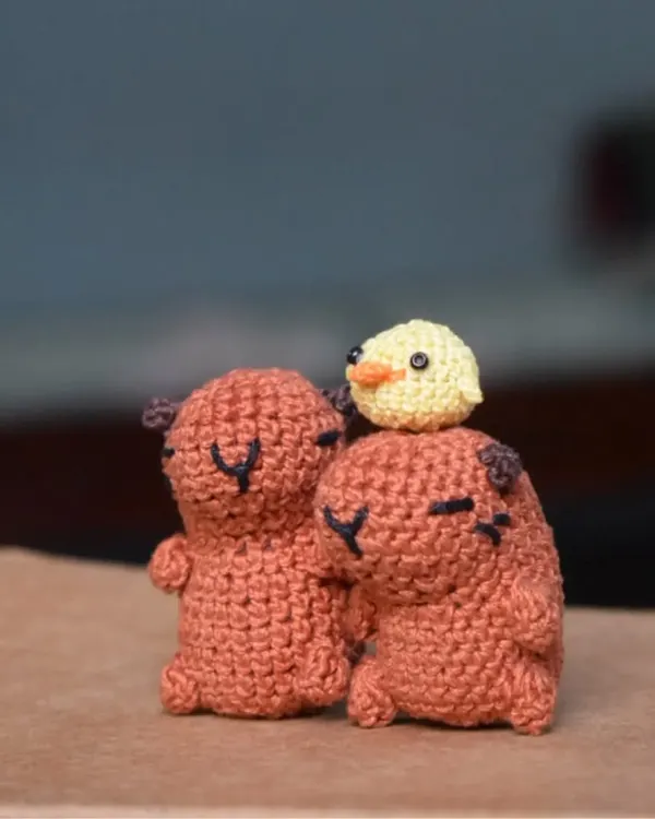 A pair of my signature crochet capybaras sharing a moment with a tiny chick on top. These desk buddies are perfect for bringing a bit of calm and cuteness to your day.