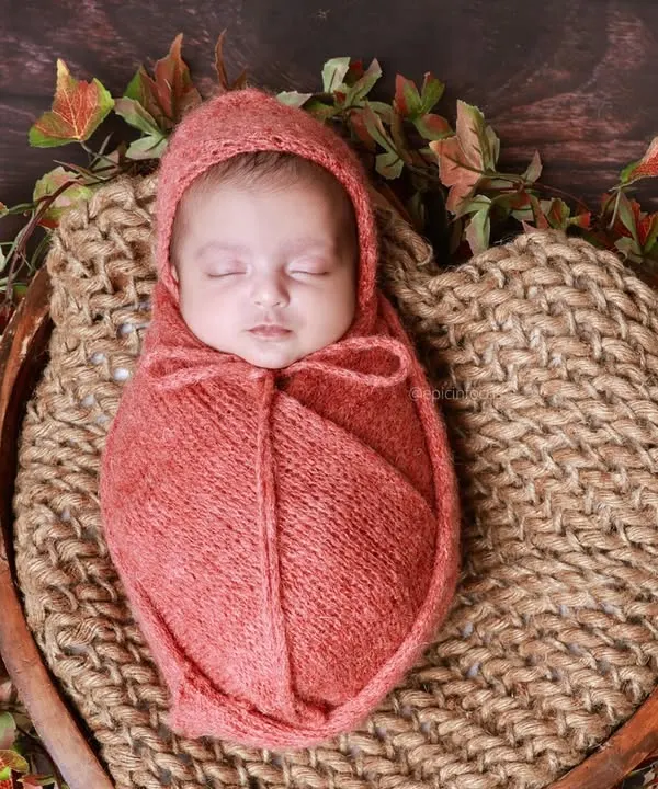 A portrait of one of the twins from a vintage-themed session, wrapped in a warm, rust-colored swaddle. We capture individual portraits in addition to shots of the pair together.