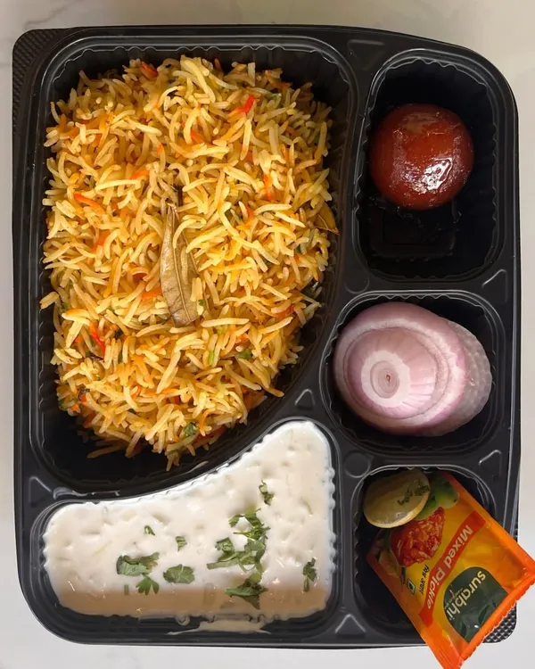 Our customizable meal boxes are ideal for corporate lunches or events. This box features a delicious vegetable biryani, raita, gulab jamun, and onion salad, providing a complete and satisfying meal.