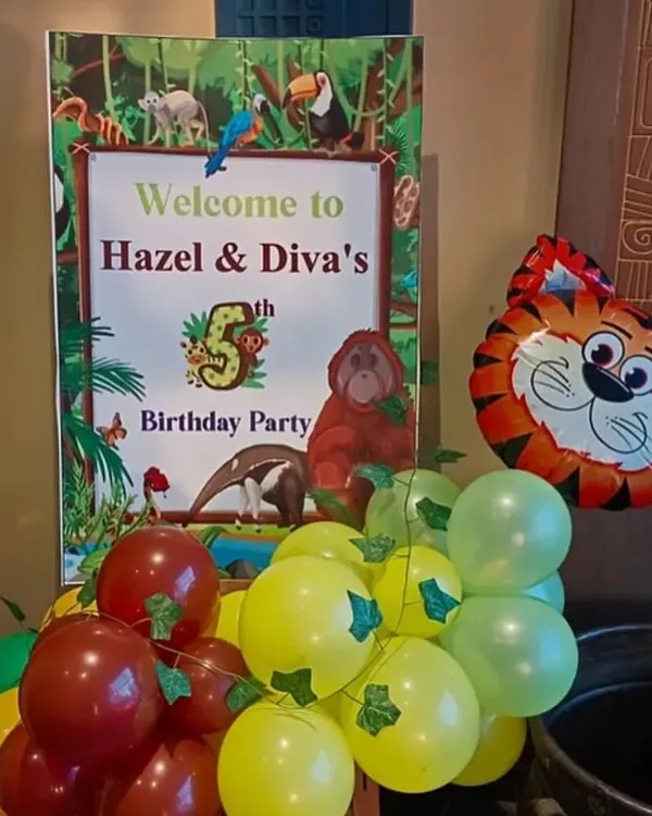 A personalized welcome sign for a jungle-themed 5th birthday party. The sign is complemented by a small balloon cluster and an animal-shaped foil balloon to set the theme from the entrance.