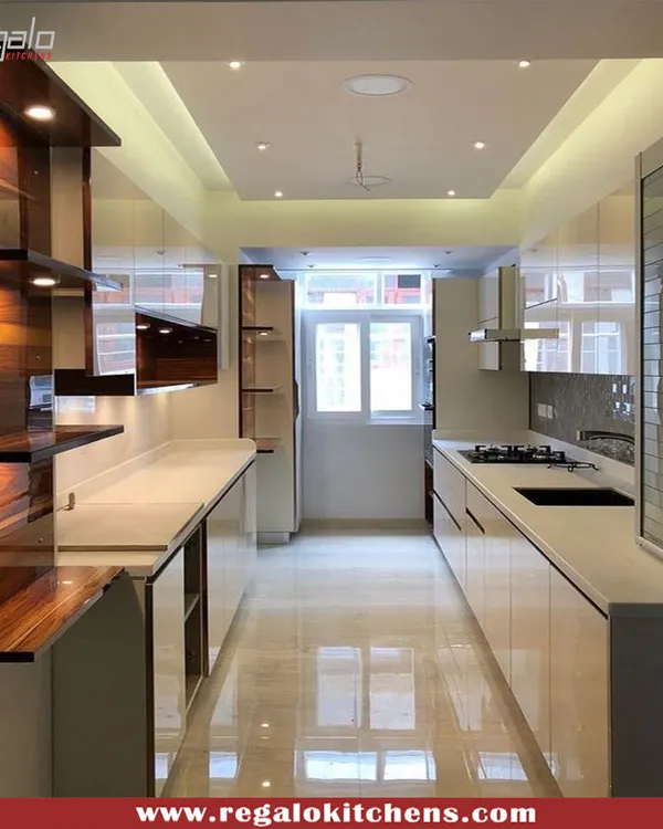 This parallel kitchen showcases a stunning blend of high-gloss white cabinetry and rich wood shelving. The layout maximizes storage and workspace in a narrow area, with reflective surfaces and good lighting creating a sense of openness.