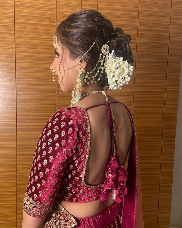 A classic messy bun adorned with a string of fresh gajra (jasmine flowers). This is a timeless choice for a traditional Indian wedding ceremony, offering a beautiful fragrance and a classic bridal feel.