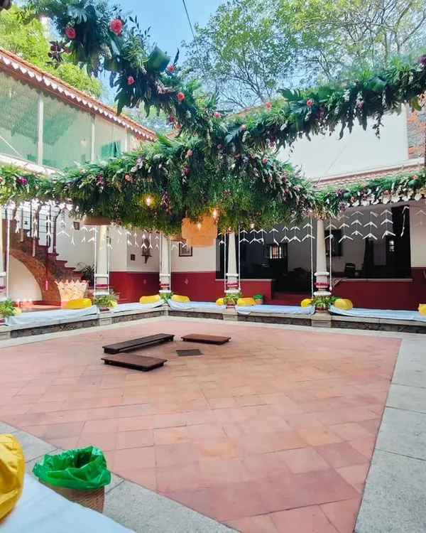 We decorated this beautiful heritage home's courtyard for a traditional wedding ceremony. The setup features lush green foliage garlands crisscrossing the open space, with floral accents and traditional pillar wraps, creating an elegant and natural ambiance for the wedding rituals.
