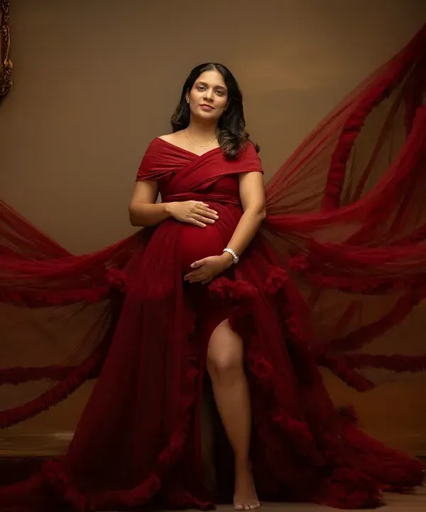A powerful portrait in a magnificent red gown. The flowing fabric creates a sense of motion and drama, perfectly highlighting the beauty of the baby bump in this studio maternity photo.