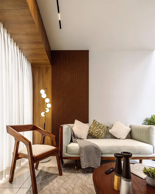 A beautifully lit living room corner, featuring a modern wooden armchair and a sleek sofa. This shot highlights the warm and inviting atmosphere created by the blend of natural textures and contemporary furniture.