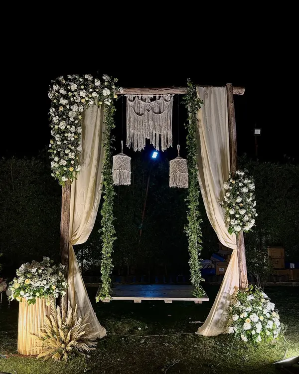 This dreamy boho-chic swing was the perfect photo spot for a 25th anniversary. We used rustic wood, flowing drapes, lush white florals, and delicate macrame details to create a romantic and elegant setting for the happy couple.