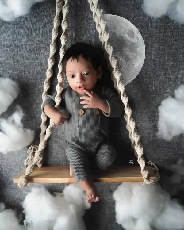 Twinkle, twinkle, little star. This baby boy looks right at home on his swing, set against a night sky with a glowing moon and fluffy clouds.