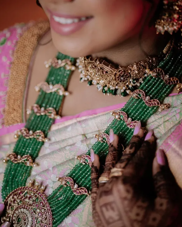 A close-up of a bride's stunning green beaded necklace and the intricate details of her saree.