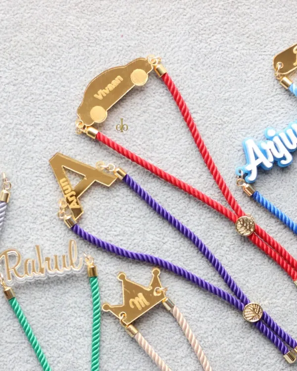 A vibrant collection of our personalized acrylic Rakhis. You can customize them with names, initials, or fun shapes like cars and crowns, making each one truly unique.