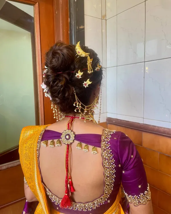 A detailed view of a traditional Marathi Khopa, or bridal bun, adorned with a classic chandrakor moon accessory and other delicate gold pins.