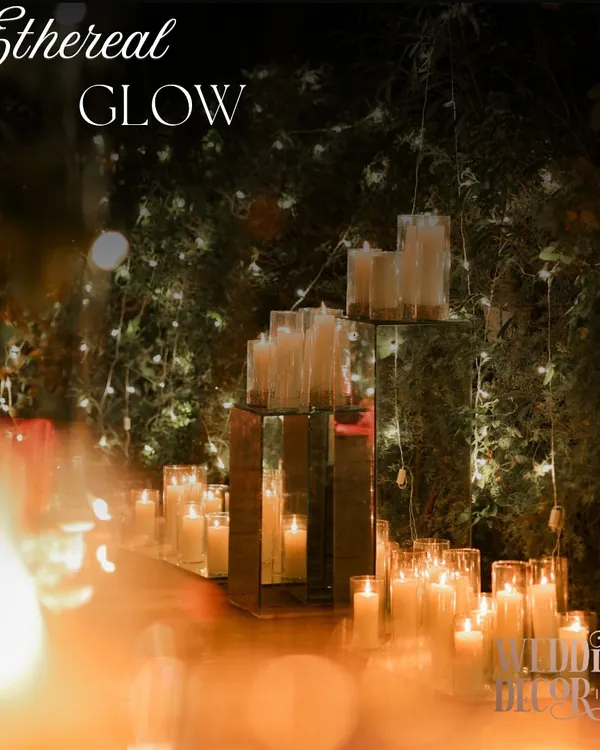 An aisle defined by an ethereal glow. We used hundreds of candles in glass hurricanes, placed on mirrored platforms to multiply their light and create a truly magical, shimmering effect.