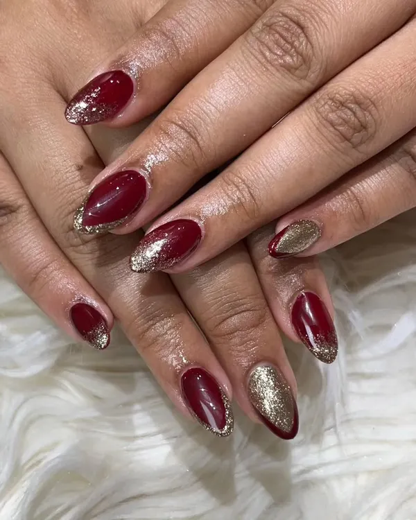 A classic bridal look featuring deep red gel polish on almond-shaped extensions, accented with a brilliant gold glitter ombre. This is a perfect choice for making a statement on your wedding day.