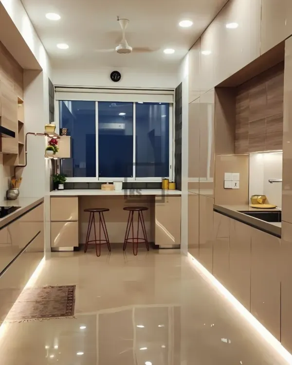 This is what I mean by making space work harder in Bombay. This parallel kitchen layout maximizes counter and storage space without feeling cramped. Notice the seamless glossy cabinets and integrated breakfast bar by the window, creating a bright, functional area for cooking and casual meals.