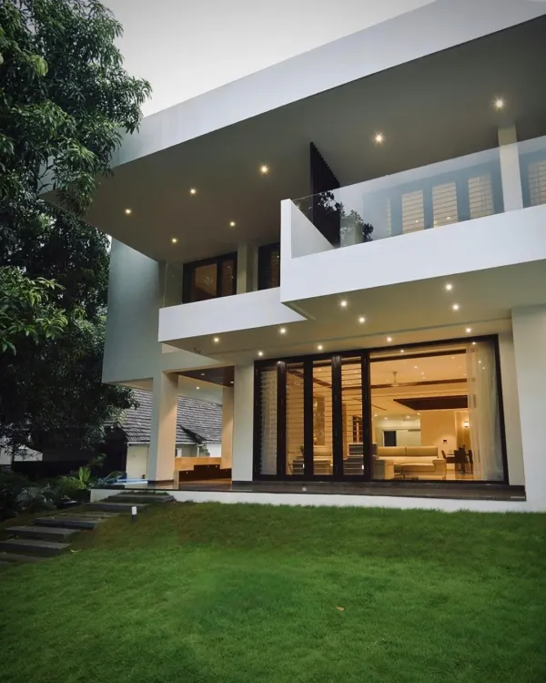 This home's facade features floating edges and expansive glass doors that open onto a lush lawn, blurring the boundary between the living room and the garden. The design creates a dialogue between the structure and the elements.