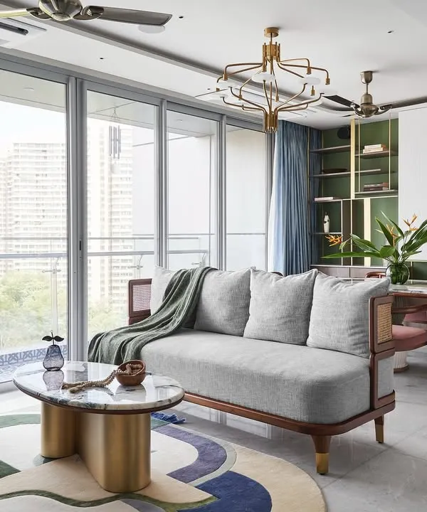 The living room of the "Whimsical House," featuring a custom 3-seater sofa and lounge chairs that blend wood and cane for a Zen-like feel. The centerpiece is the 'Ananta' table, with its infinity-shaped brass base and Patagonia marble top.