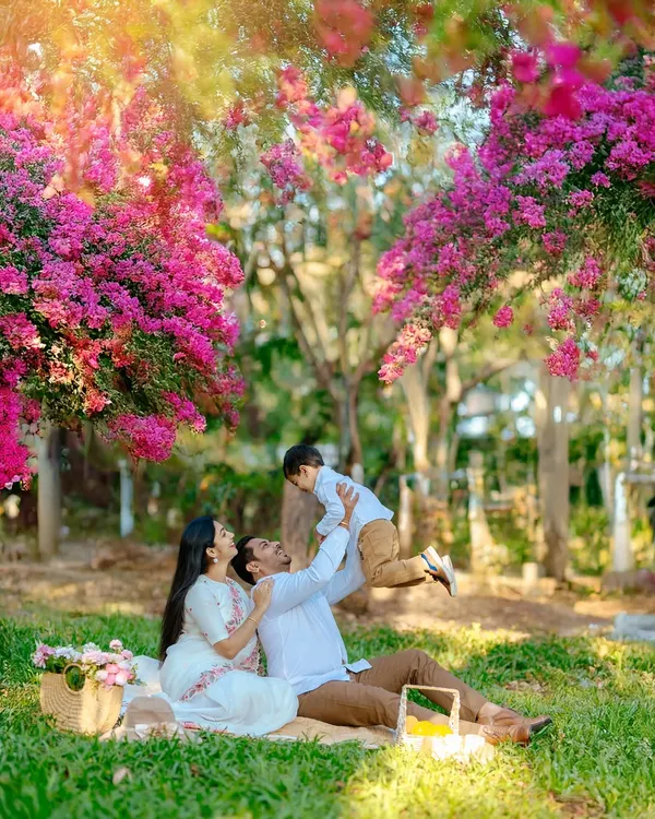 We believe the best family portraits are the ones filled with life and laughter. This moment of pure joy, with a father lifting his son under a canopy of bright bougainvillea, captures the playful, energetic spirit we love to bring out in our outdoor family photoshoots.