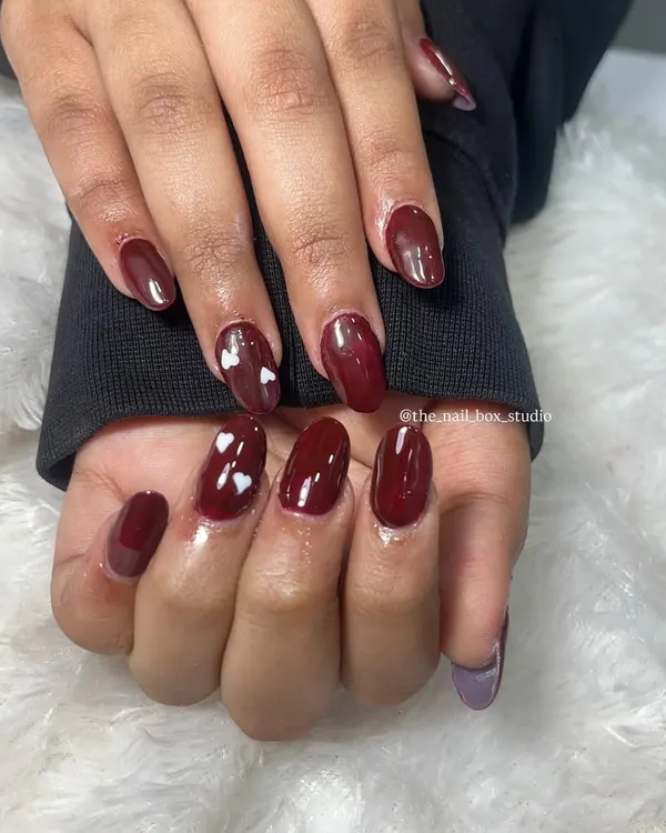 A beautiful and simple set of acrylic extensions with a deep, glossy maroon gel polish. I added a few tiny, hand-painted white hearts for a sweet and subtle touch of art.