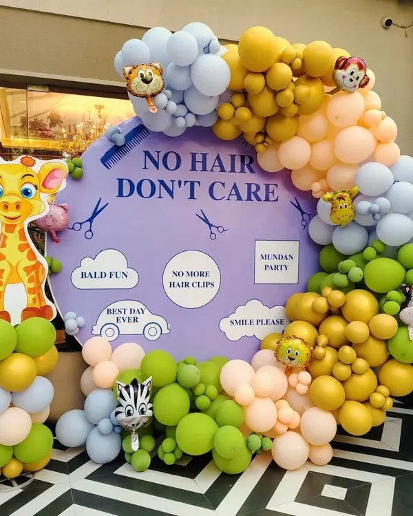 A fun and cheeky photo booth for a Mundan ceremony. The "No Hair, Don't Care" theme is brought to life with a custom backdrop surrounded by a playful jungle-themed balloon garland, creating a perfect spot for happy pictures.