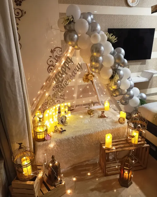 A romantic anniversary surprise at home. This beautiful cabana tent setup is decorated with white and silver balloons, fairy lights, and candle-lit lanterns, creating a magical and intimate atmosphere.
