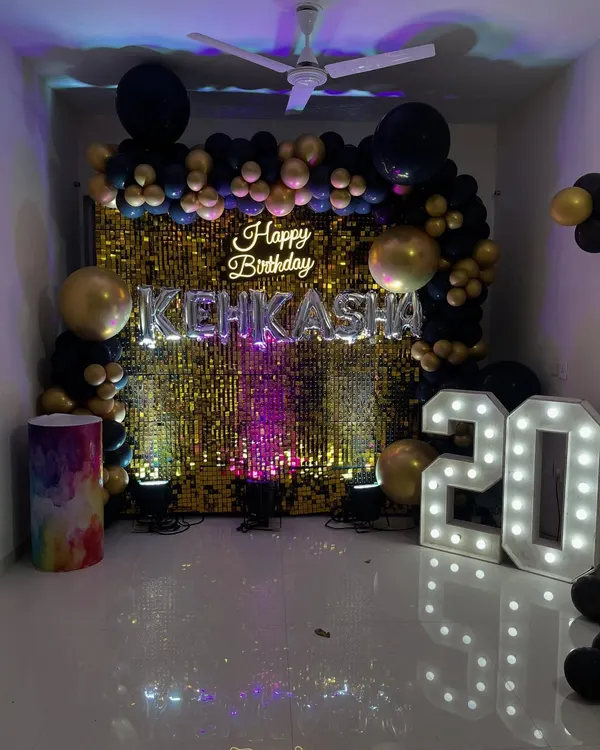A stunning gold shimmer wall serves as the centerpiece for this 20th birthday. Paired with a neon sign and a black and gold balloon arch, it creates an unforgettable photo backdrop.