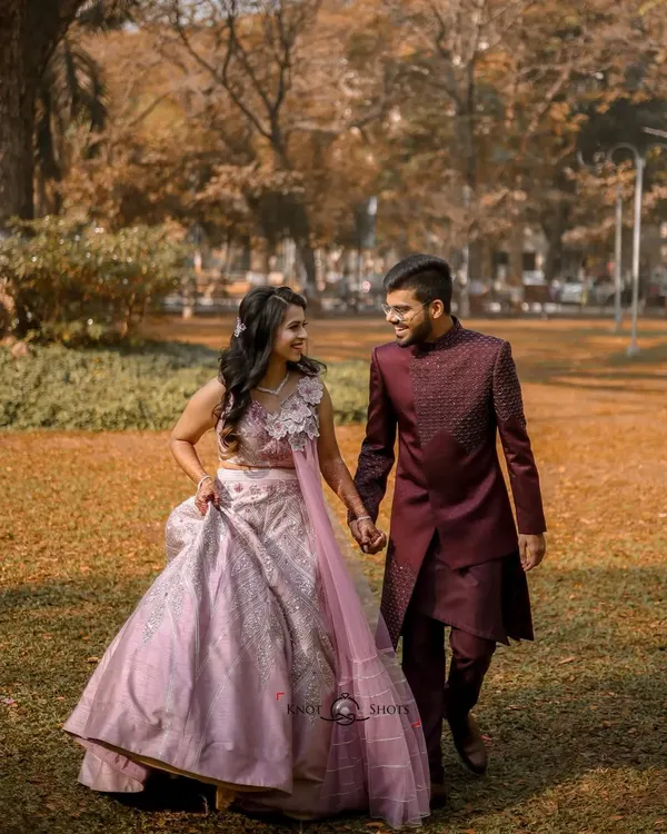 A classic engagement portrait of the couple walking hand-in-hand through a park. Their elegant ethnic wear and the beautiful autumn colors create a timeless and romantic image.
