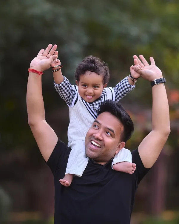 A fun and energetic shot of a boy on his dad's shoulders, reaching for the sky. This pose is always a favorite for capturing the playful side of the father-son relationship.
