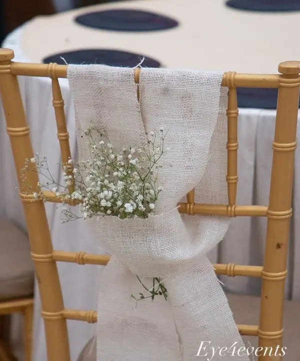 A small detail that adds a lot of charm. We decorated the guest chairs with a simple drape of rustic linen fabric and a small posy of baby's breath for a touch of understated elegance.