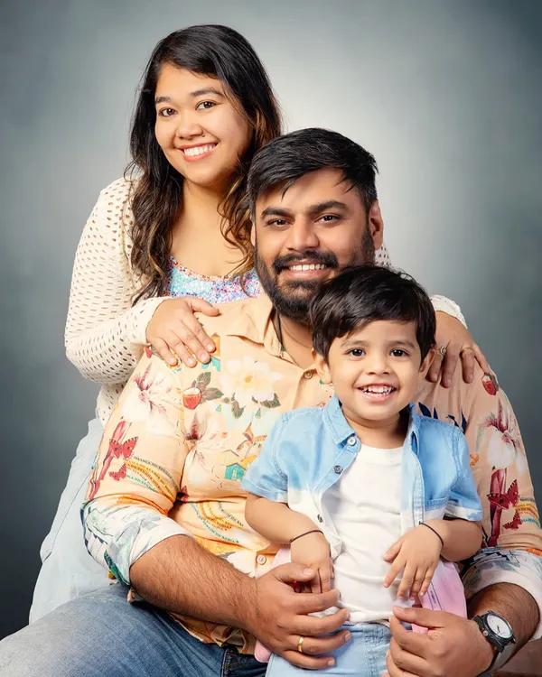 A beautiful, classic family portrait. The simple grey backdrop puts all the focus on the family's happy smiles and the loving connection between them.