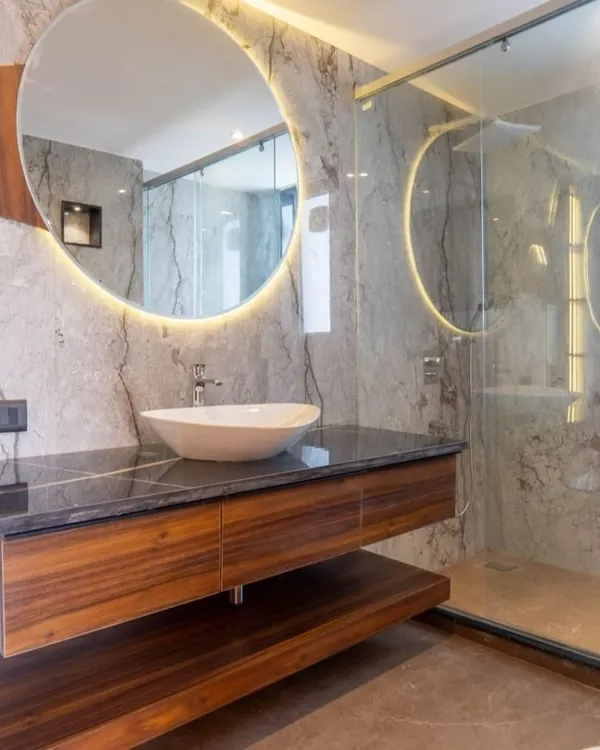 A bathroom should feel like a personal spa. Here, I used large-format marble tiles, a floating wood vanity, and a backlit circular mirror to create a space that is clean, modern, and radiates calm.