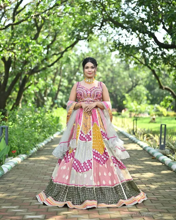 A stunning full-view of a multi-color patchwork lehenga. This design combines panels of pink, yellow, and grey with traditional bandhani and mirror work for a truly unique festive look.