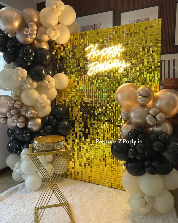 Our gold sequin shimmer wall provides the ultimate glamorous backdrop for any celebration. Here, we've paired it with a 'Happy Birthday' neon sign and an organic balloon garland in black, white, and chrome gold for a chic and modern party look.