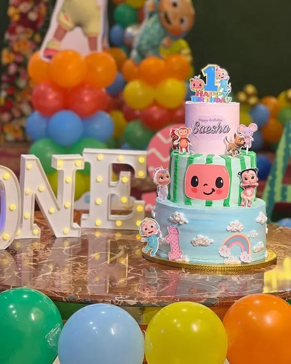 A vibrant two-tier Cocomelon cake, perfect for a first birthday party, set up beautifully at the venue.