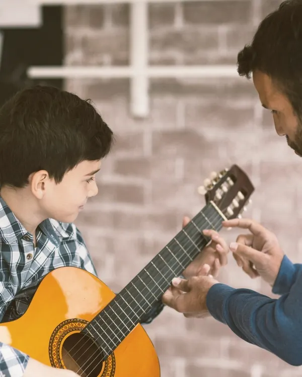 We believe in personalized attention to help every student find their unique sound. Here, one of our instructors guides a young guitarist through proper hand positioning on the fretboard during a private acoustic guitar lesson.
