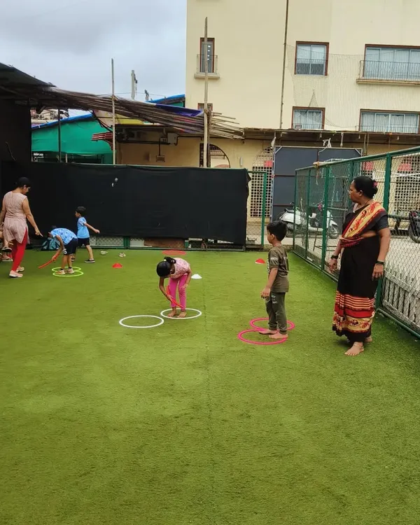 We transform any space into a super fun play zone! Here, you can see our little champs navigating an exciting obstacle course on an artificial turf, using hoops and cones to test their agility. It's a fantastic way for kids to burn off energy and improve their coordination while cheering each other on.
