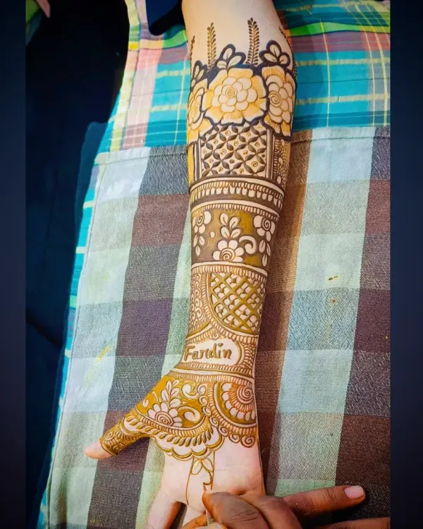 A close-up of a bridal design featuring bold, beautiful flowers on the forearm. The shading technique makes the petals stand out.