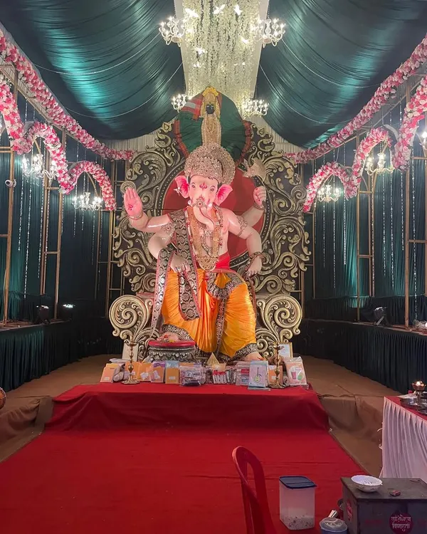 We create magnificent community Ganpati pandals that radiate spiritual energy. This setup features a grand idol on a regal throne, illuminated by a crystal chandelier and framed by elegant green draping and floral arches.