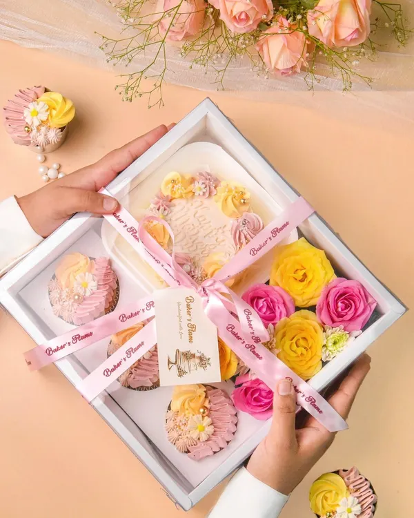 A beautiful bakery gift hamper with a mini cake, cupcakes, and fresh flowers, showcasing my skills in product and gifting photography.