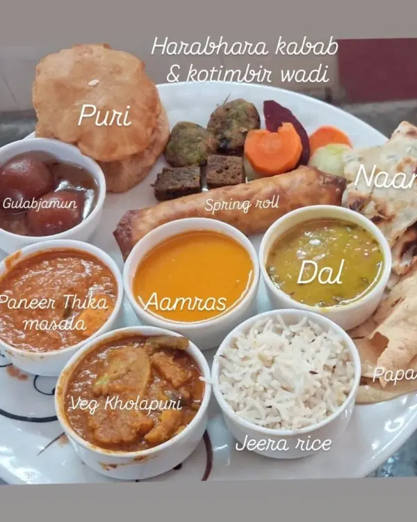 A look at the complete meal experience I provide. This plate features a variety of our popular dishes, including Paneer Tikka Masala, Veg Kolhapuri, Aamras, Dal, Jeera Rice, Puri, Naan, and starters like Harabhara Kabab and Spring Roll.