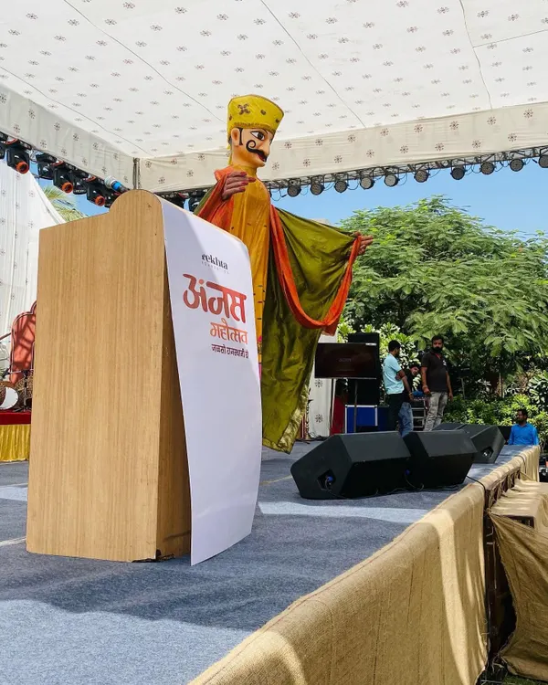 A giant puppet of a Rajasthani man stands tall on stage during the Anjas Mahotsav. These figures are designed to be focal points for large events, adding a unique and traditional touch to any modern stage setup.