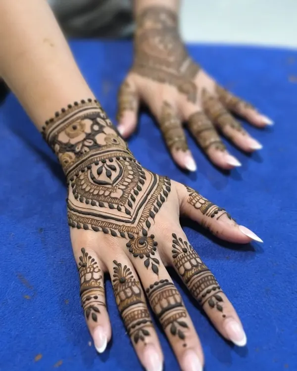 A clean and modern Arabic design. This style focuses on the back of the hand with a central motif and detailed finger work, leaving parts of the skin bare.