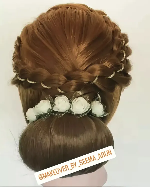 An elegant braided bun hairstyle, perfect for a reception or engagement. The delicate white flowers and glitter accents add a touch of glamour to this classic updo.
