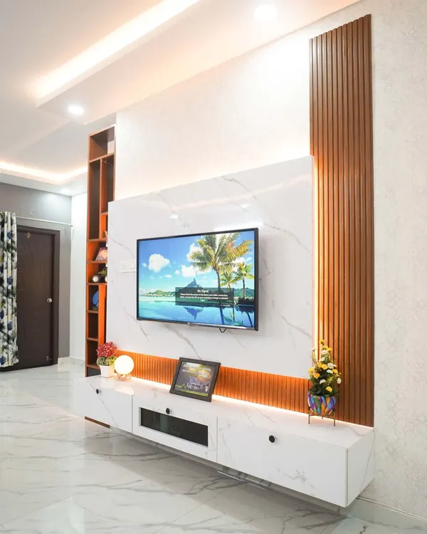A bespoke floating entertainment unit that combines a marble-finish back panel with vertical wooden fluting for a touch of modern elegance. The design includes concealed storage and warm ambient lighting, creating a sophisticated and clutter-free focal point in the living room.